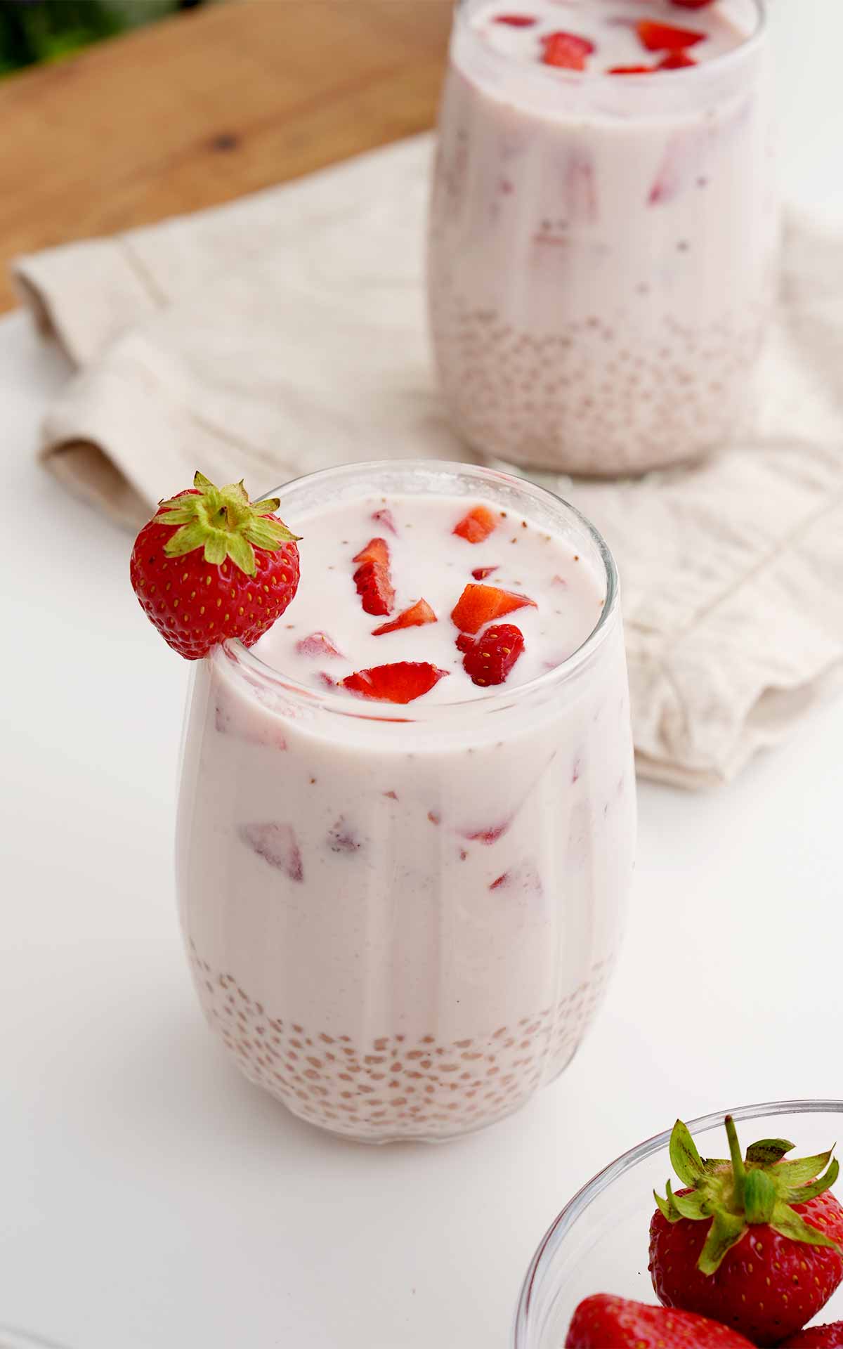 A creamy sago drink garnished with fresh strawberry, displayed on the white table.
