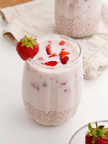 An image of a creamy sago drink with strawberries displayed on the white table.